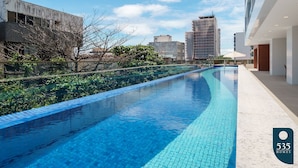 A modern hotel with a swimming pool, a view of the city, and a clear sky.