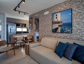 A modern living room with a brick wall, a large window, and a view of boats.