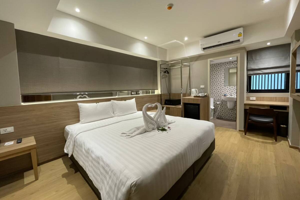 Quarto de hotel moderno com uma cama grande, uma escrivaninha, área de chuveiro e uma televisão.