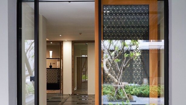 Corredor com porta estampada e vista para um jardim lá fora.
