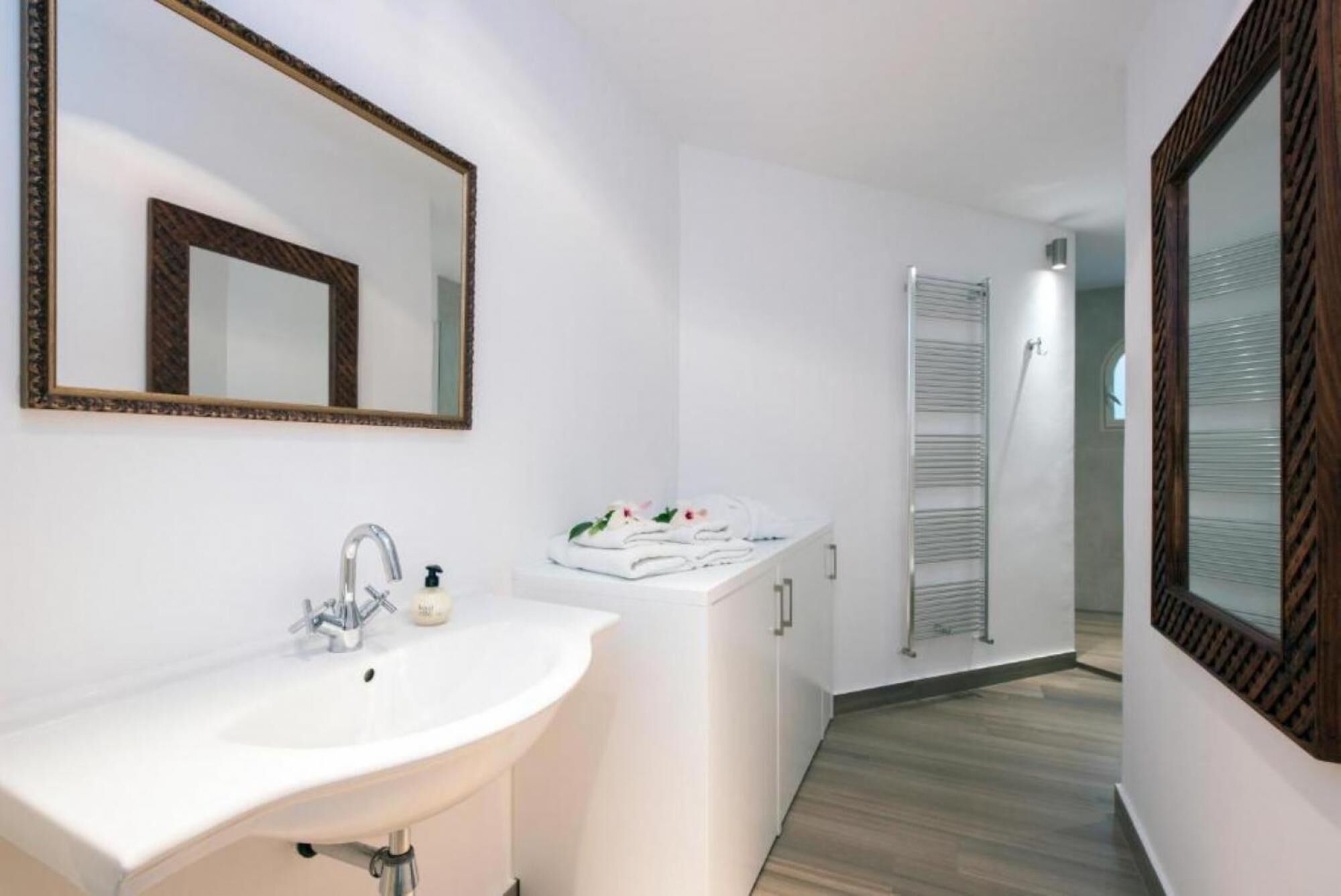 A modern bathroom with a white sink, a mirror, and a towel rack.