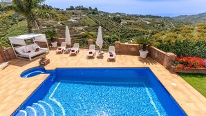 A swimming pool with lounge chairs and umbrellas, surrounded by a landscaped garden and a view of the countryside. - Villa Mirador de Frigiliana (Frigiliana)