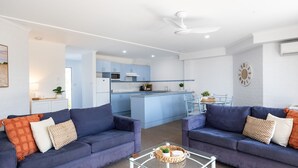 A modern living room with two sofas, a coffee table, and a kitchen in the background.