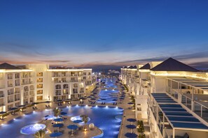 Un hotel con una piscina grande, varios balcones y un área exterior bien iluminada.