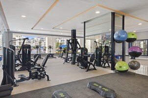 A gym with various exercise equipment, including treadmills and weight machines, and exercise balls.