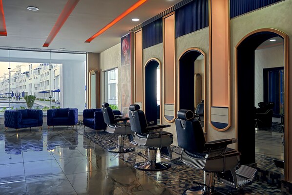 Un salón moderno con varias sillas de barbero, un espejo grande y vista a un edificio exterior.