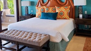 Un dormitorio con una cama grande, un cabecero de madera, dos mesitas de noche con lámparas y un ventilador de techo.