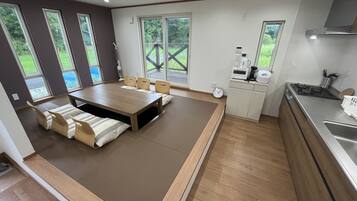 Enjoy meals around the large dining table in this open-plan living space, surrounded by cushioned seating.