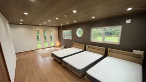 A room with three beds, a large window, and a ceiling with recessed lighting.