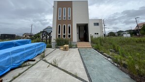 A modern two-story house with a concrete pathway leading to the entrance.