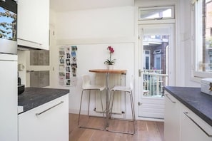 Compact kitchen with oven, water dispenser, and outdoor balcony access.