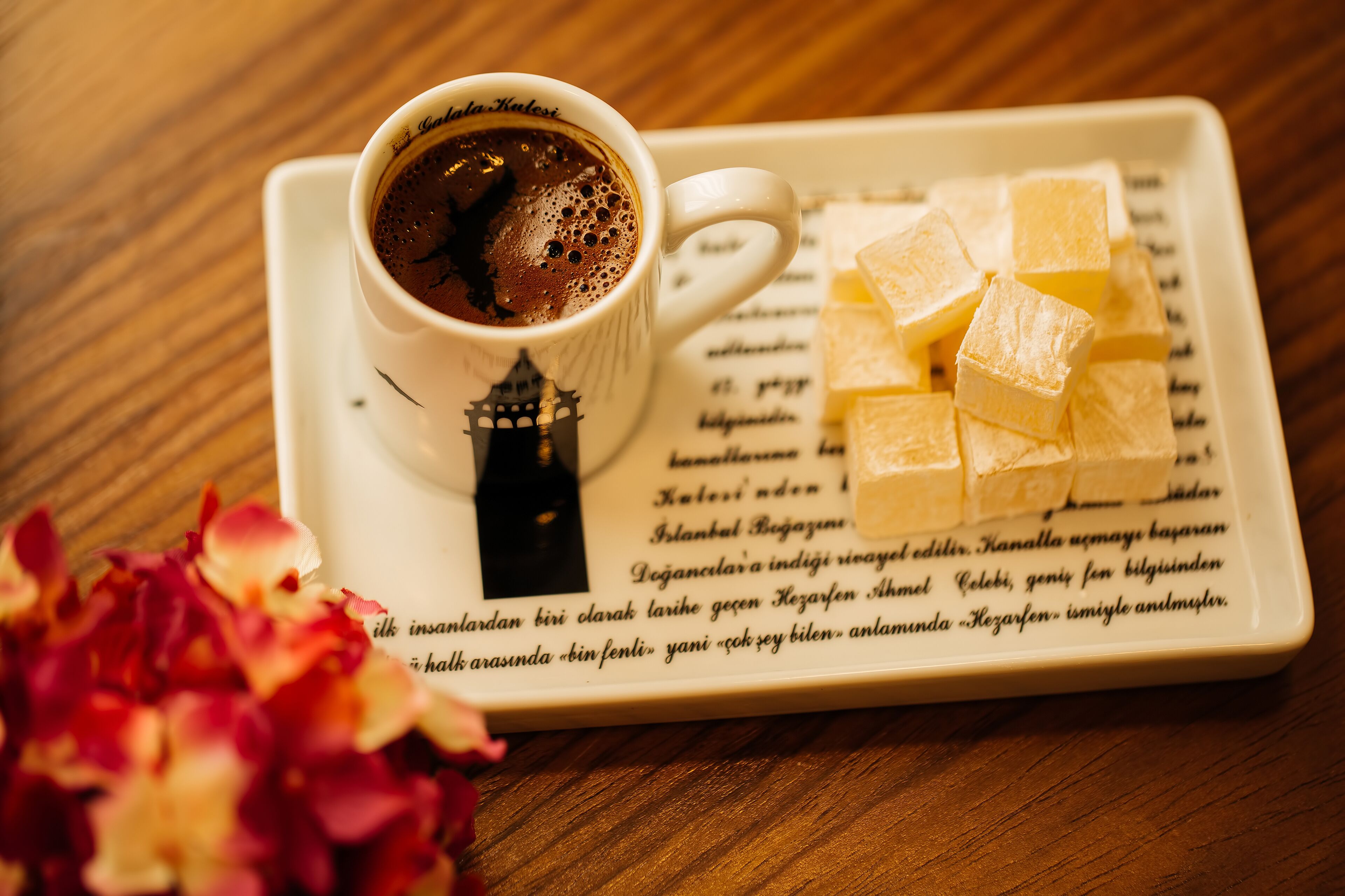 A cup of coffee on a saucer with a plate of cubes beside it.