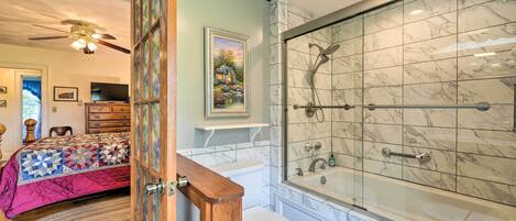 A bathroom with a glass-enclosed shower, a bathtub, and a toilet.