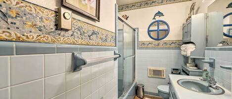 A bathroom with a shower, toilet, sink, and decorative tiles.