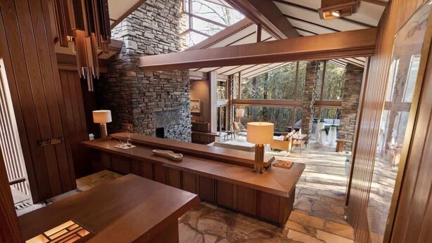 A modern kitchen with a stone fireplace, wooden beams, and large windows. - Hunter House - Hot tub & movie theater (Memphis)