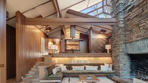 A spacious living area with a stone fireplace, wooden beams, and a cozy seating arrangement. - Hunter House - Hot tub & movie theater (Memphis)
