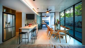 A modern kitchen with a central island, bar stools, and a dining area with wooden chairs and a glass table.