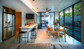 Enjoy meals in the kitchen and dining area, featuring a refrigerator, oven, and TV, with a glass table and comfortable seating.