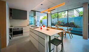 Enjoy meals in the spacious kitchen and dining area with a central island, featuring a dishwasher, oven, and microwave, and a dining table with chairs and a bar stool.