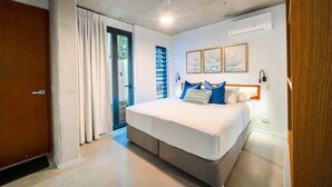 A bedroom with a large bed, a door, a window, and a wall-mounted air conditioner.