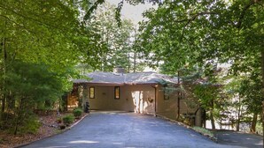 Une maison avec une allée menant à un garage, entourée d’arbres.