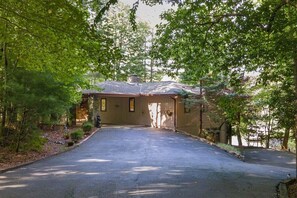 A house with a driveway leading to a garage, surrounded by trees.