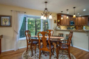 A dining area with a wooden table, chairs, and a chandelier.