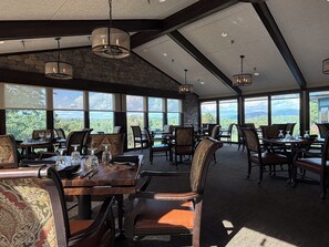 A spacious dining area with high ceilings and large windows offering a view of the mountains.