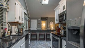 A kitchen with a granite countertop, stainless steel appliances, and a tiled floor. - Peace of Heaven in Connestee Falls (Brevard)