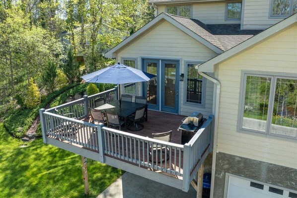 A house with a deck, a table with chairs, and a blue umbrella.