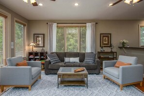 A living room with a sofa, two armchairs, a coffee table, and a bookshelf.