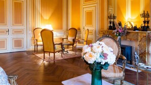 A luxurious room with a large mirror, ornate wooden paneling, a chandelier, and a floral arrangement on a table. - Chateau du Hallay (Montaigu-Vendée)