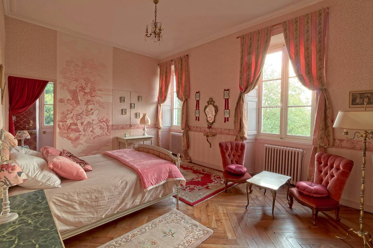 Quarto com cama, duas cadeiras, uma mesa e um radiador.