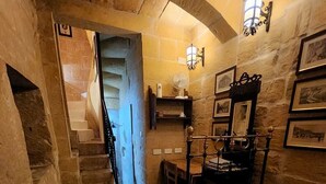 A cozy room with a bed, a small table, and a staircase leading to another area. - 2 Bed House Sleeps 3 - Wifi, Aircon, Balcony (Valletta)