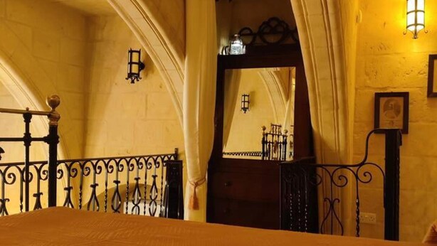 A room with a bed, a wooden headboard, a mirror, and a wall-mounted light fixture. - 2 Bed House Sleeps 3 - Wifi, Aircon, Balcony (Valletta)