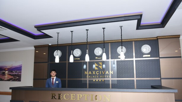 A reception desk at Naxçivan Palace Hotel with clocks and a nameplate. - Naxçıvan Palace Hotel (Nakhchivan)