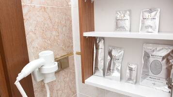 A bathroom with a hairdryer, shelves with various toiletries, and a shower cap.