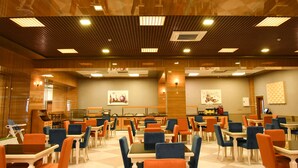 A spacious hotel lobby with a checkered floor, multiple dining tables and chairs, and a central kitchen area. - Naxçıvan Palace Hotel (Nakhchivan)