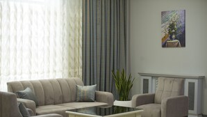 A living room with a sofa, armchairs, a coffee table, and a potted plant. - Naxçıvan Palace Hotel (Nakhchivan)