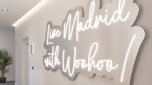 Una pared con un letrero de neón que dice 'Live Madrid with Woohoo!'