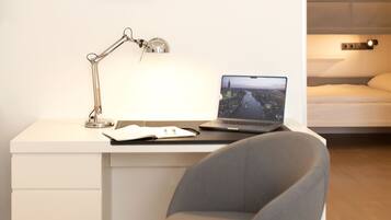 A modern workspace with a laptop, a desk lamp, and a notebook.