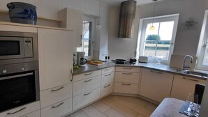 A modern kitchen with built-in appliances, a large window, and a view of the outdoors. - The Eichengold Hideaway (Handrup)