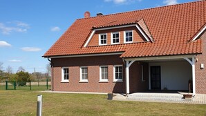 A two-story brick house with a red-tiled roof, a covered porch, and a grassy yard. - The Eichengold Hideaway (Handrup)