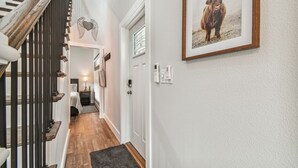 Un escalier avec des marches en bois et une rampe noire. Un tableau encadré représentant un taureau est accroché au mur.
