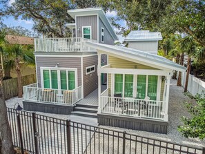 Une maison à deux étages avec un balcon, une véranda et une cour clôturée.