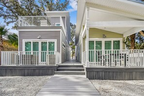 Two houses connected by a covered walkway, surrounded by a gravel driveway and landscaped gardens.