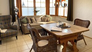 A cozy dining area with a wooden table, wicker chairs, and a sofa.