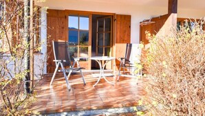 A patio with a table and chairs, wooden shutters, and a view of the outdoors.
