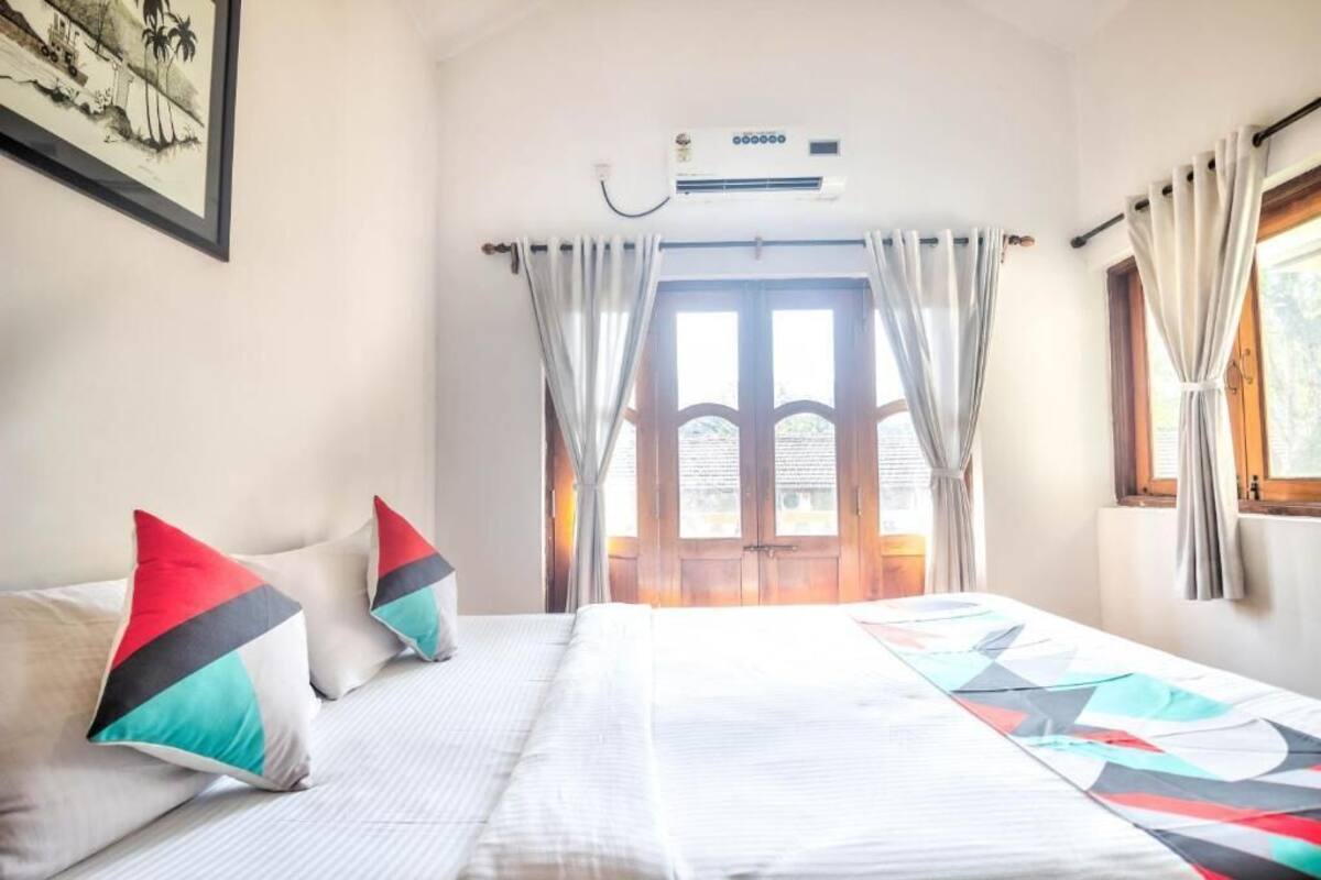Ein Hotelzimmer mit Bett, Vorhängen, einer Klimaanlage und einem Fenster mit Vorhängen.