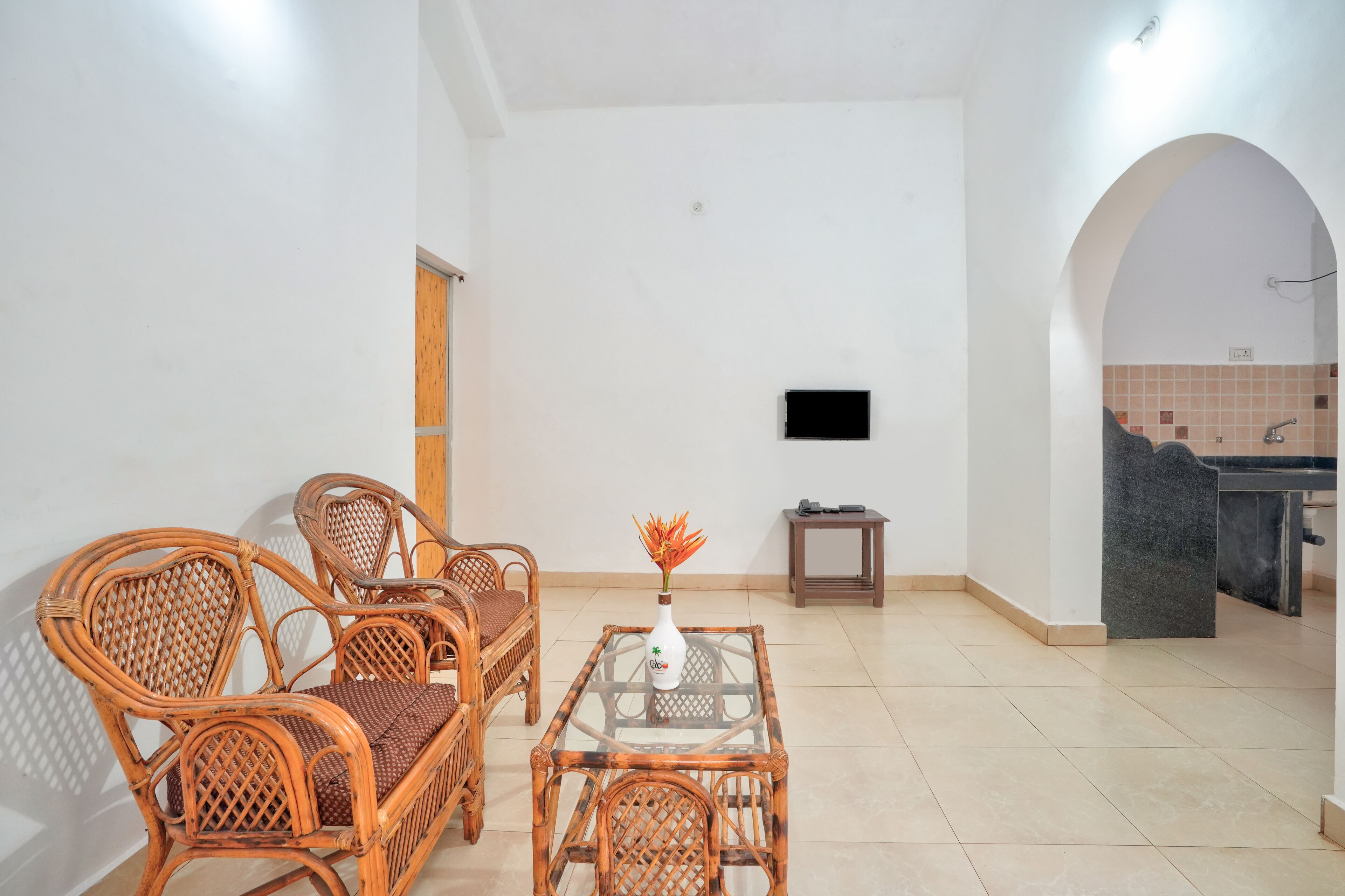 Una habitación con una mesa de comedor y sillas, un televisor pequeño en la pared y suelo de baldosas.